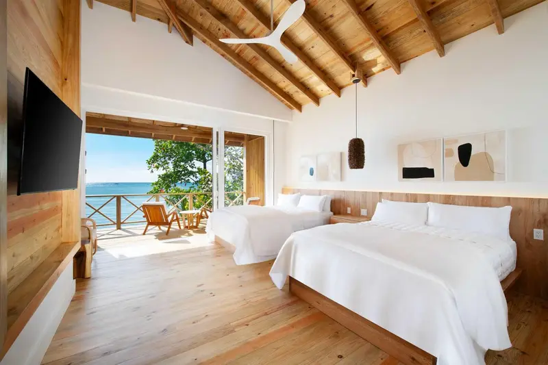 Une chambre lumineuse avec deux lits et une vue sur la mer.