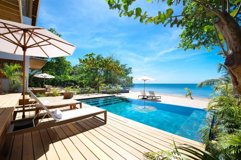 Terrasse en bois avec transats et piscine face à la mer.