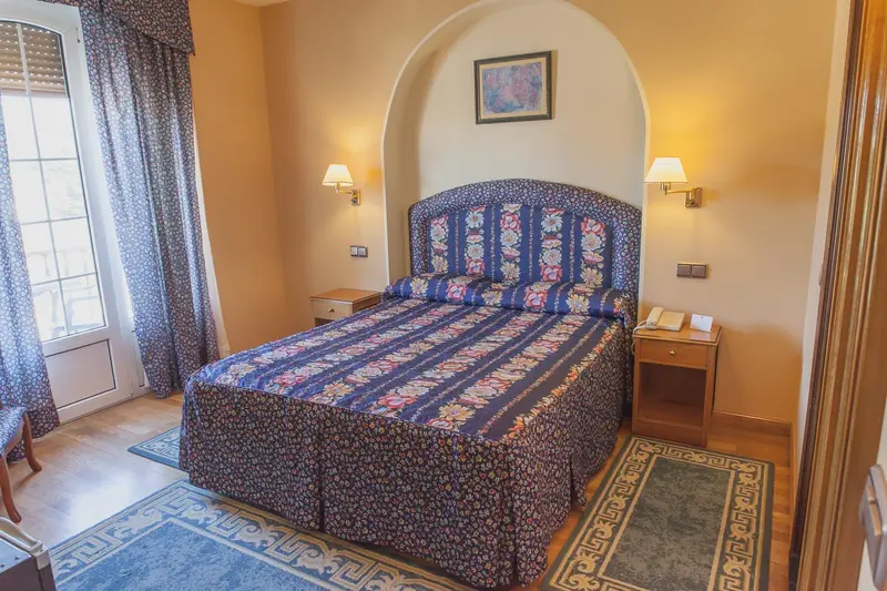 Une chambre lumineuse avec un grand lit recouvert d'une courtepointe à motifs.