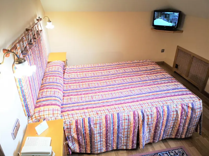 Une chambre lumineuse avec un lit recouvert d'une courtepointe colorée.