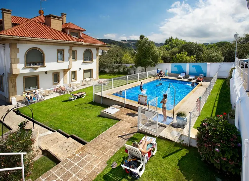 Une piscine rectangulaire bordée d'une pelouse verdoyante et de transats.