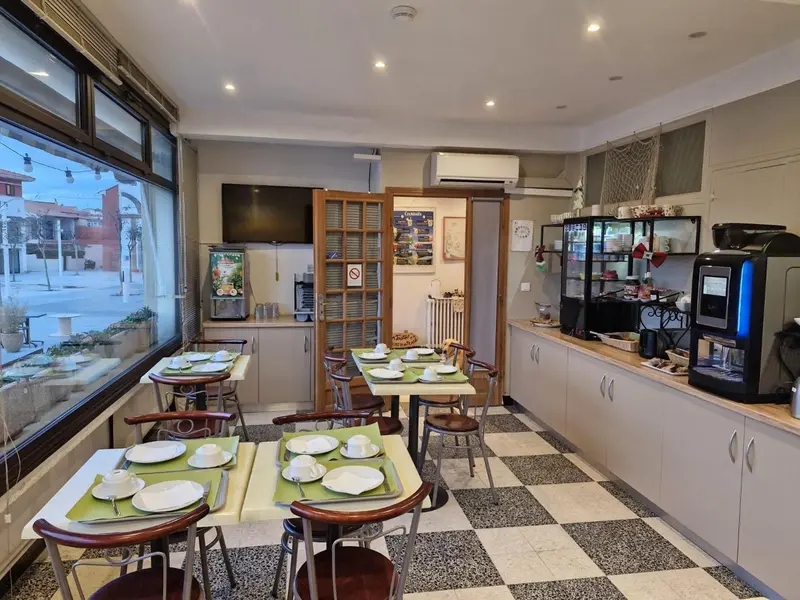 Une salle lumineuse avec des tables dressées pour le petit-déjeuner.