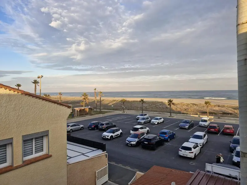 Vue d'un parking et d'une plage depuis un balcon.