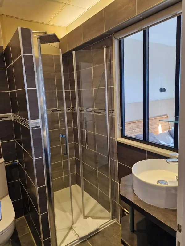 Douche à l'italienne dans une salle de bain moderne avec carrelage brun.