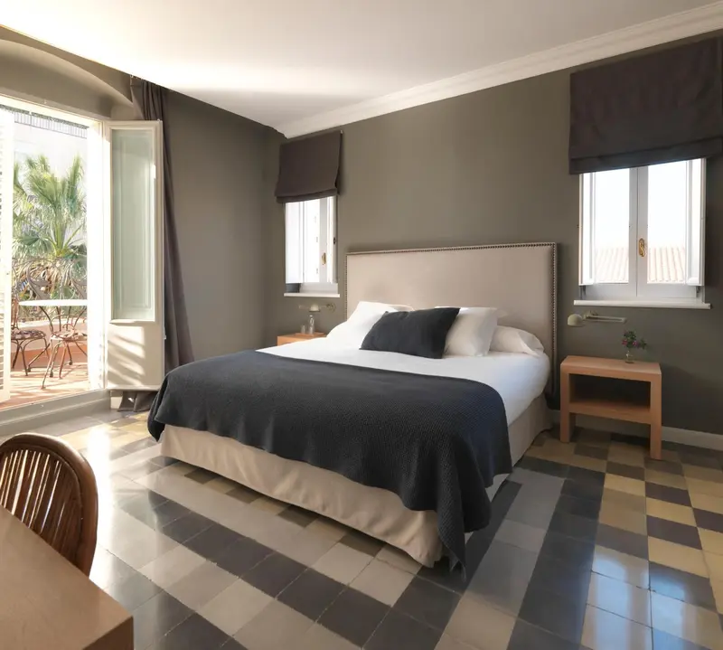 Une chambre lumineuse avec un grand lit et un accès à une terrasse.