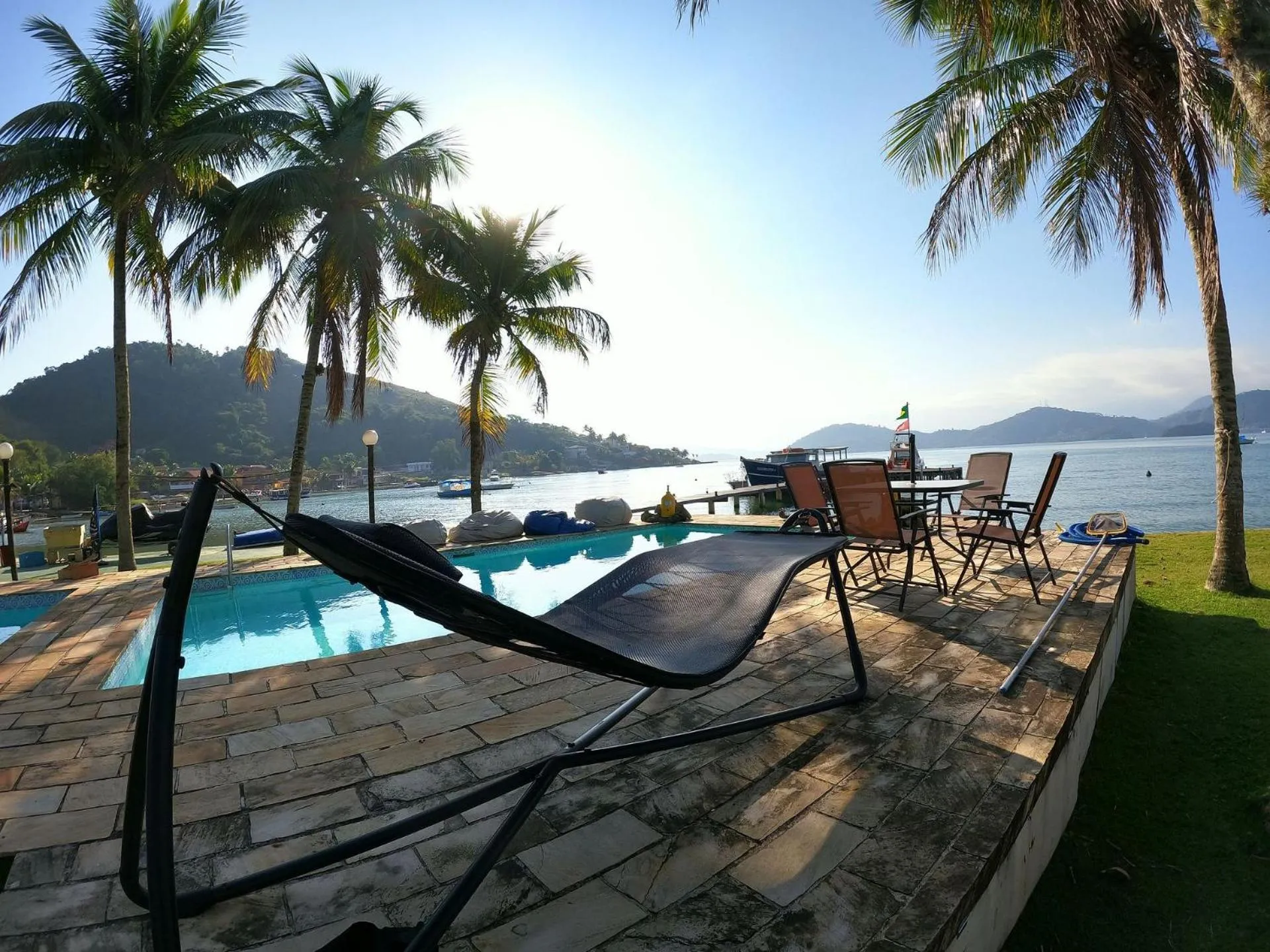 Terrasse avec transats et hamac au bord d'une piscine face à la mer.