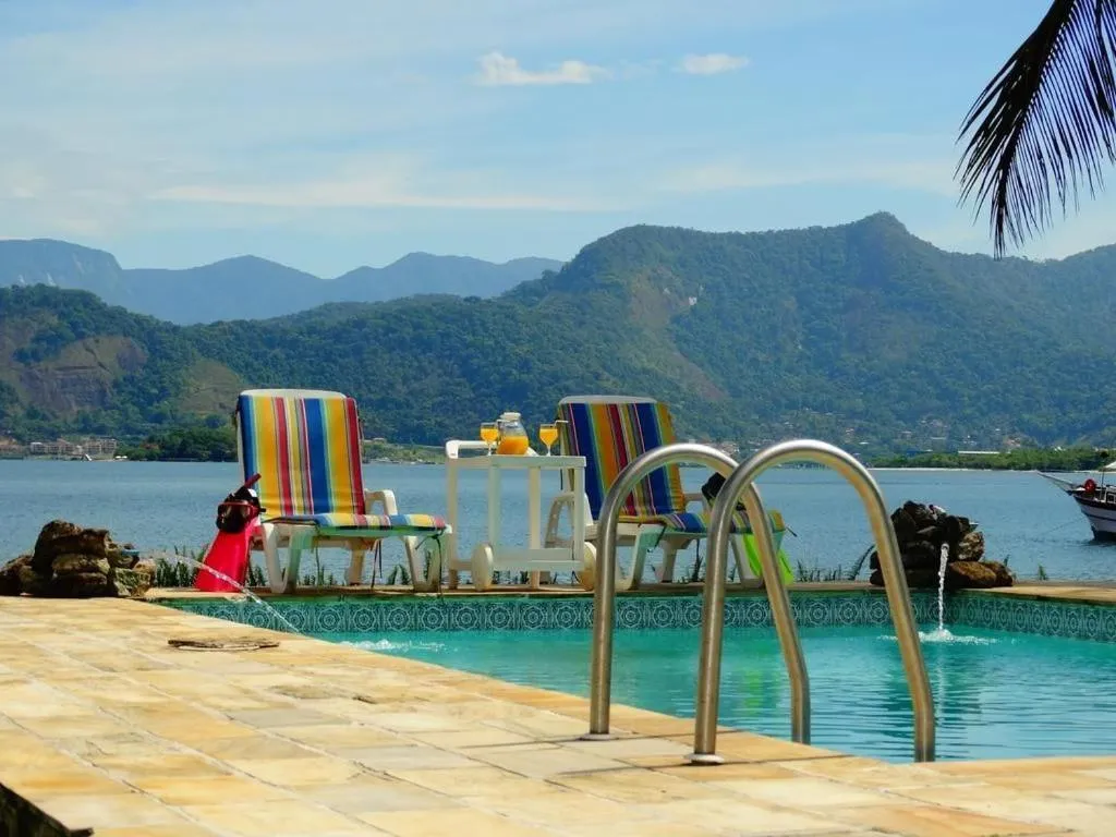 Transats colorés au bord d'une piscine avec vue sur la mer et les montagnes.