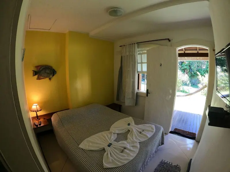 Une chambre lumineuse avec un lit décoré de serviettes et une porte ouverte sur une terrasse.