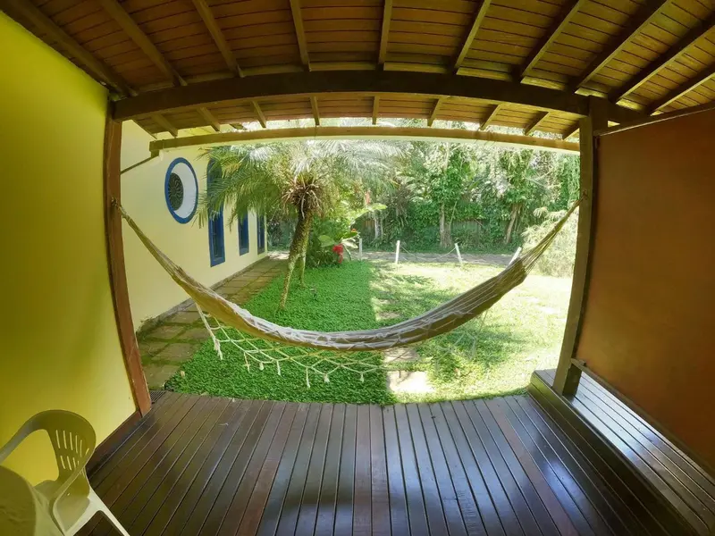Vue d'une terrasse en bois donnant sur un jardin tropical avec un hamac.