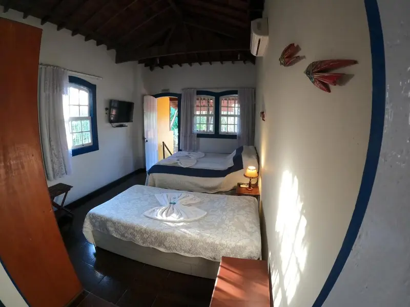 Chambre lumineuse avec deux lits simples et une décoration murale colorée.