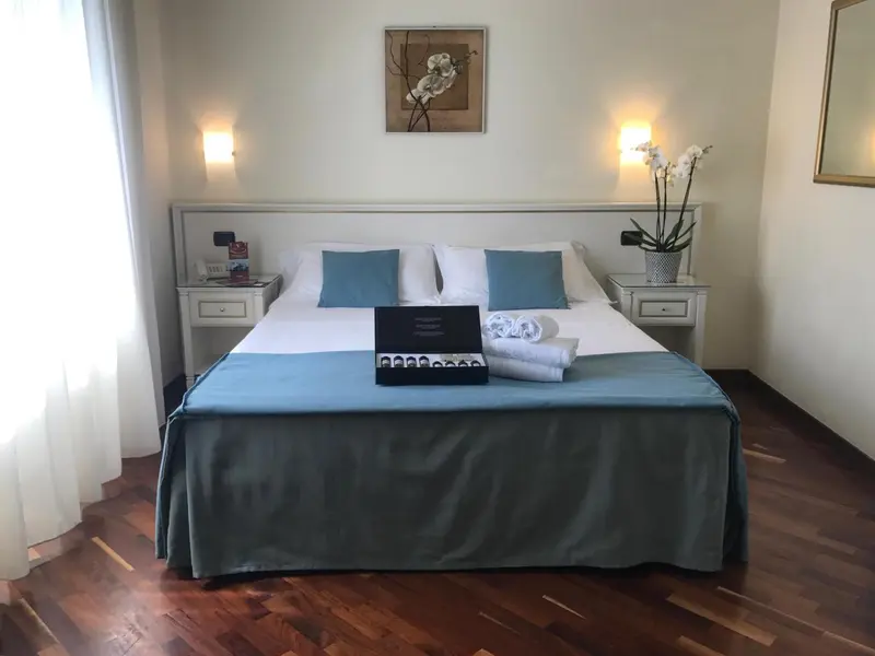 Une chambre lumineuse avec un grand lit recouvert d'une courtepointe turquoise et de coussins assortis.