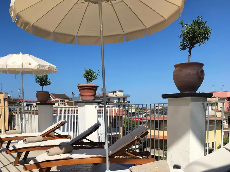 Terrasse avec transats et pots de fleurs sous le soleil.