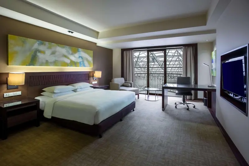 Chambre moderne avec un grand lit et un bureau près d'une fenêtre.