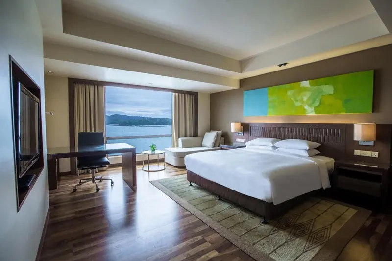 Chambre lumineuse avec un grand lit et une vue sur la mer.