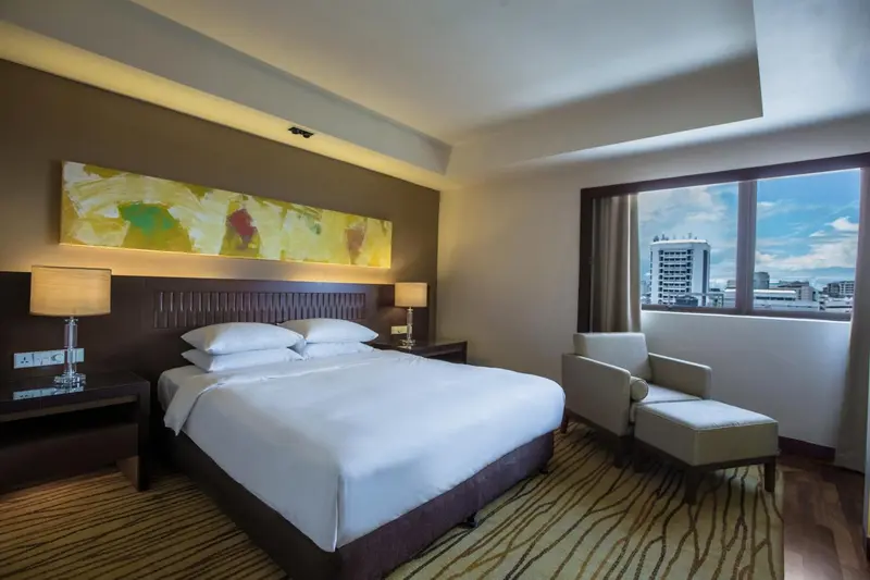 Une chambre d'hôtel lumineuse avec un grand lit et un fauteuil.