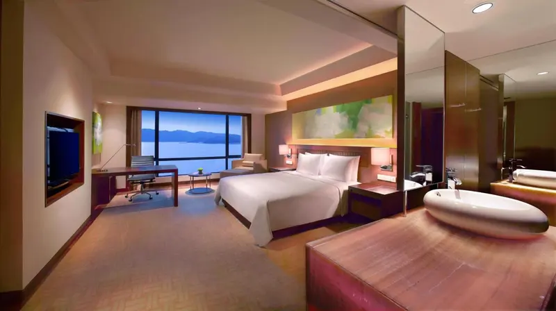 Chambre lumineuse avec un grand lit et une vue sur la mer.