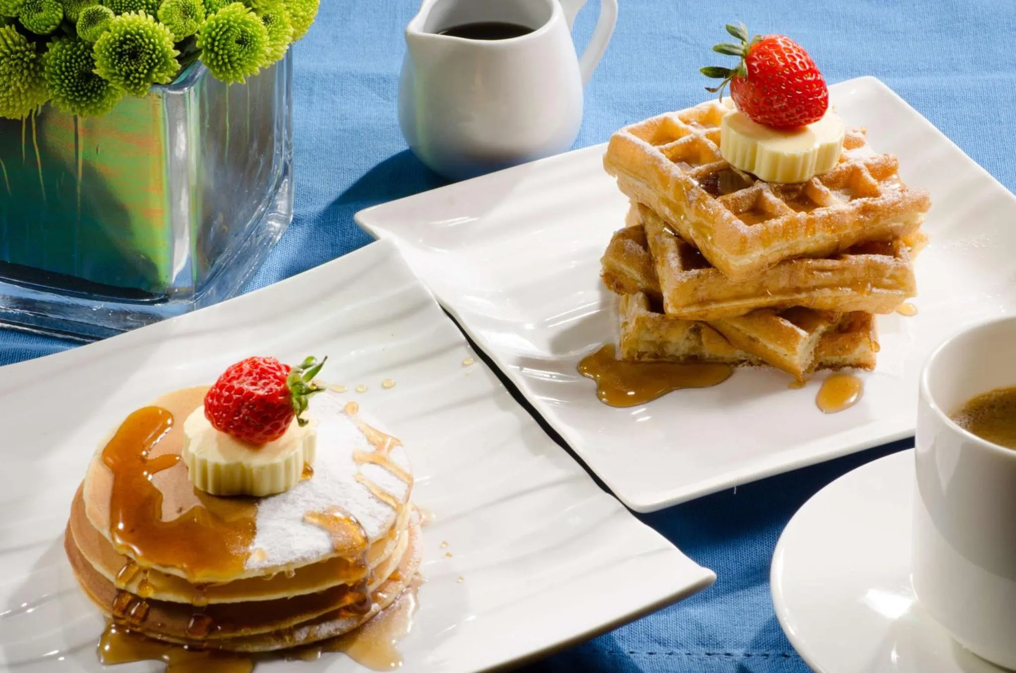 Assiettes de gaufres et de crêpes décorées de fruits et nappées de sirop.