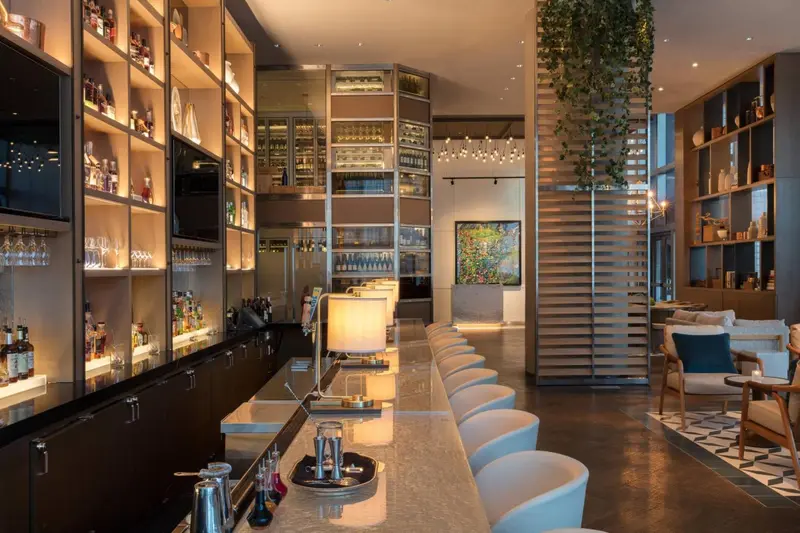 Un long comptoir de bar avec des tabourets, éclairé par des suspensions décoratives.