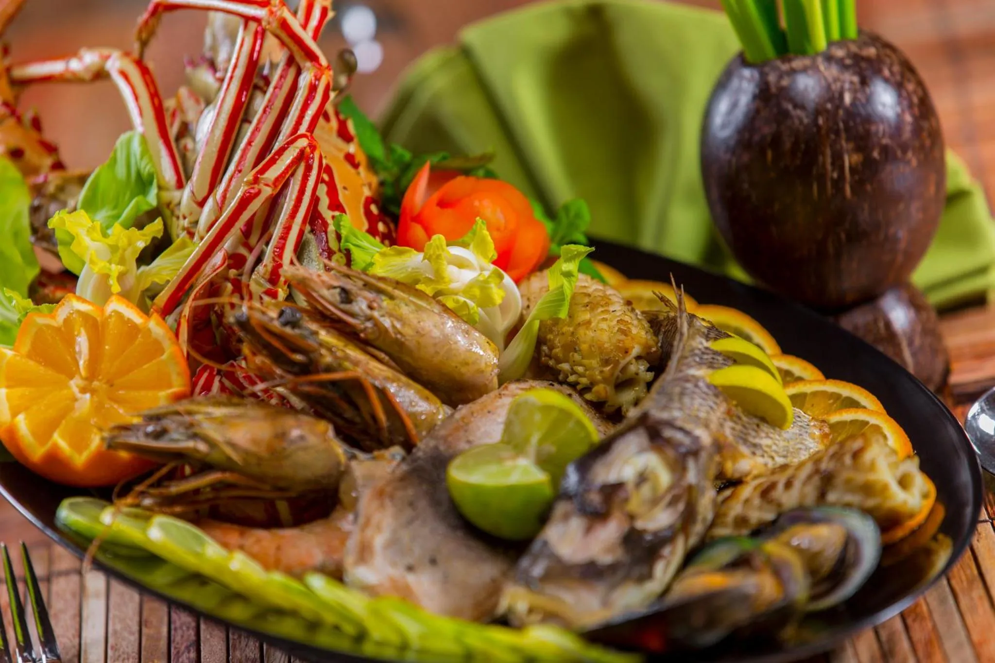 Assiette de fruits de mer et de poissons décorée de légumes et d'agrumes.