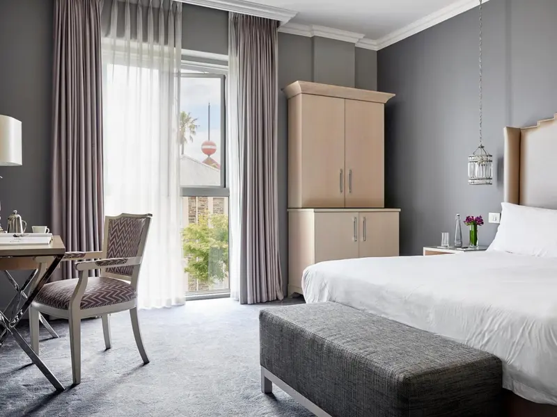 Une chambre lumineuse avec un lit, un bureau et un accès à une fenêtre.