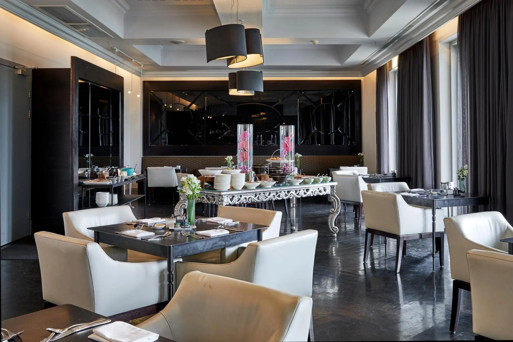 Une salle de restaurant élégante avec des tables dressées et un buffet.