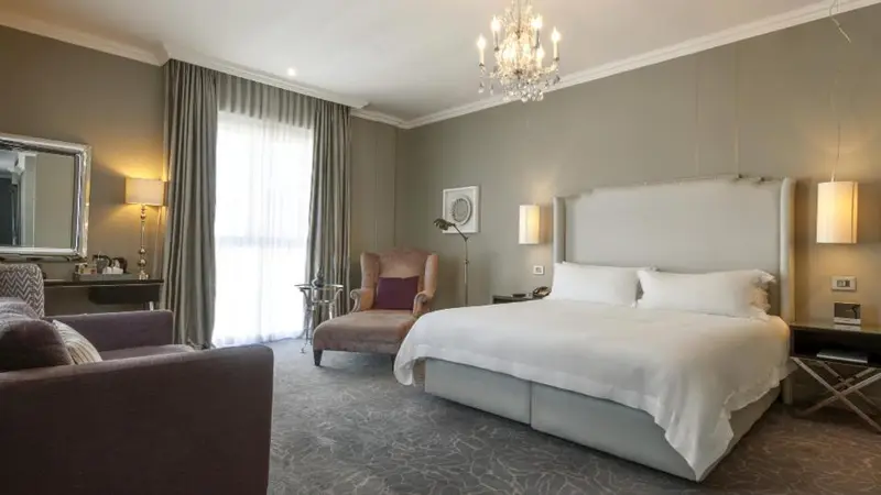 Une chambre lumineuse avec un grand lit et un fauteuil.