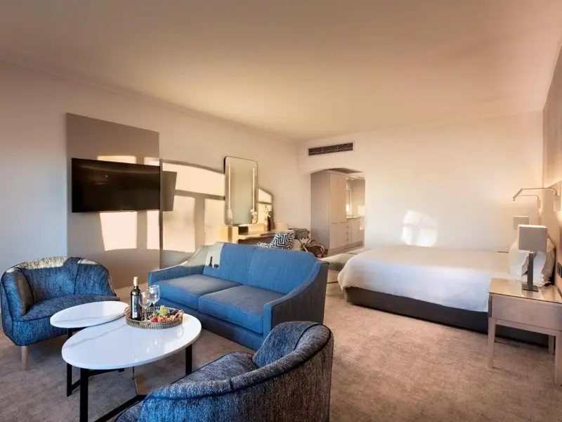 Espace de vie lumineux avec canapés, table basse et lit.