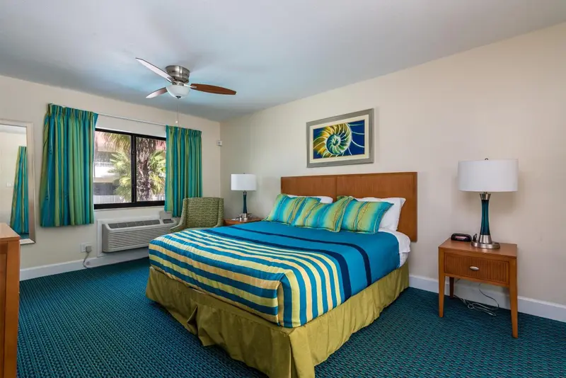 Une chambre lumineuse avec un grand lit recouvert d'une courtepointe colorée.