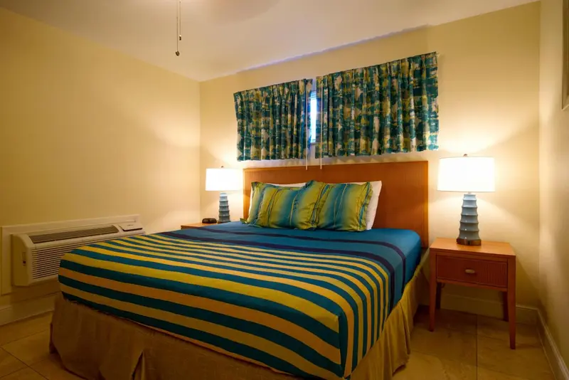 Une chambre lumineuse avec un grand lit recouvert d'une couette rayée.