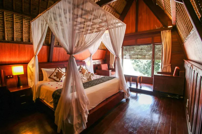 Une chambre avec un lit à baldaquin décoré de moustiquaire et de coussins.