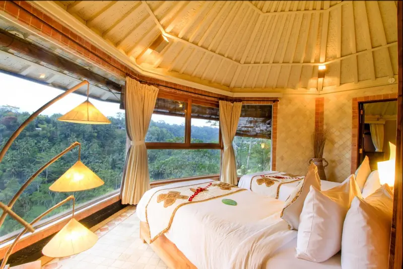 Une chambre avec un grand lit et une vue sur la végétation.