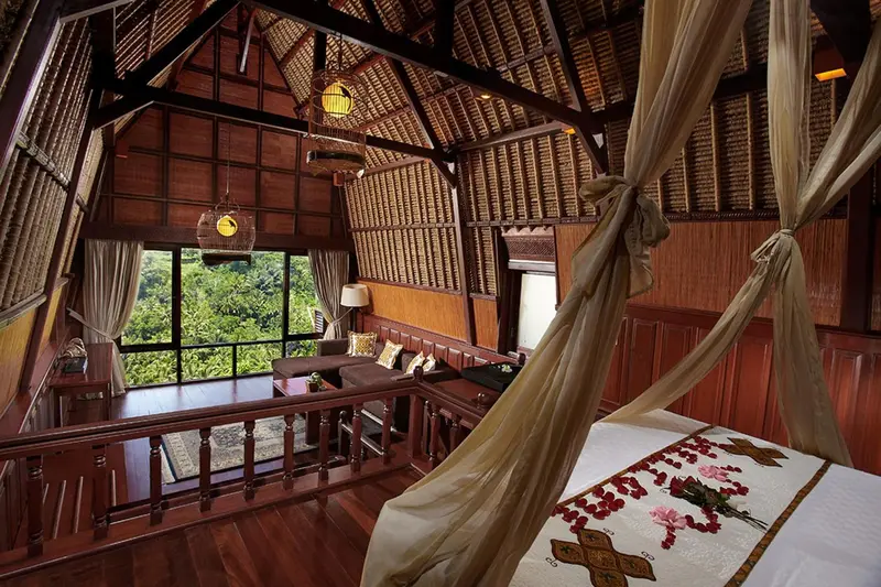 Une chambre spacieuse en bois avec un lit à baldaquin et une vue sur la végétation.
