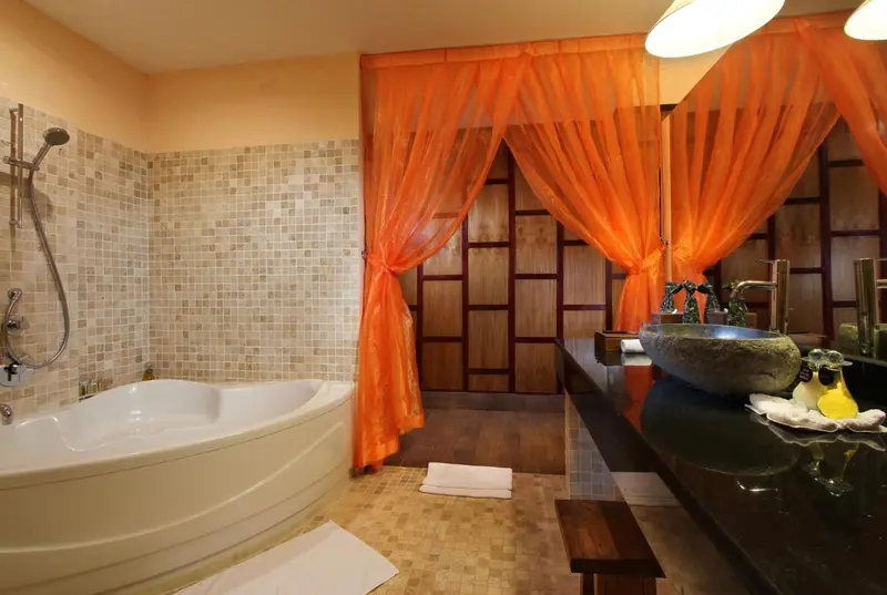 Une salle de bain lumineuse avec baignoire et vasque en pierre.