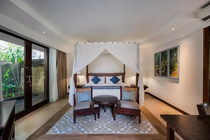 Une chambre lumineuse avec un grand lit à baldaquin et une décoration soignée.