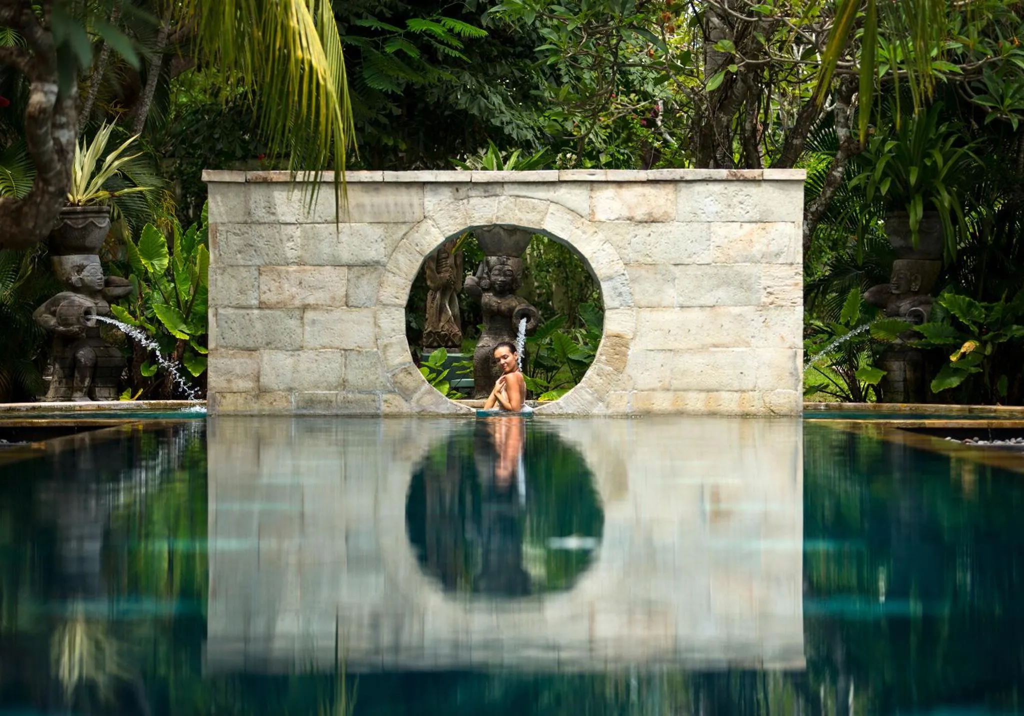 Une femme se détend dans une piscine au milieu d'une végétation luxuriante.
