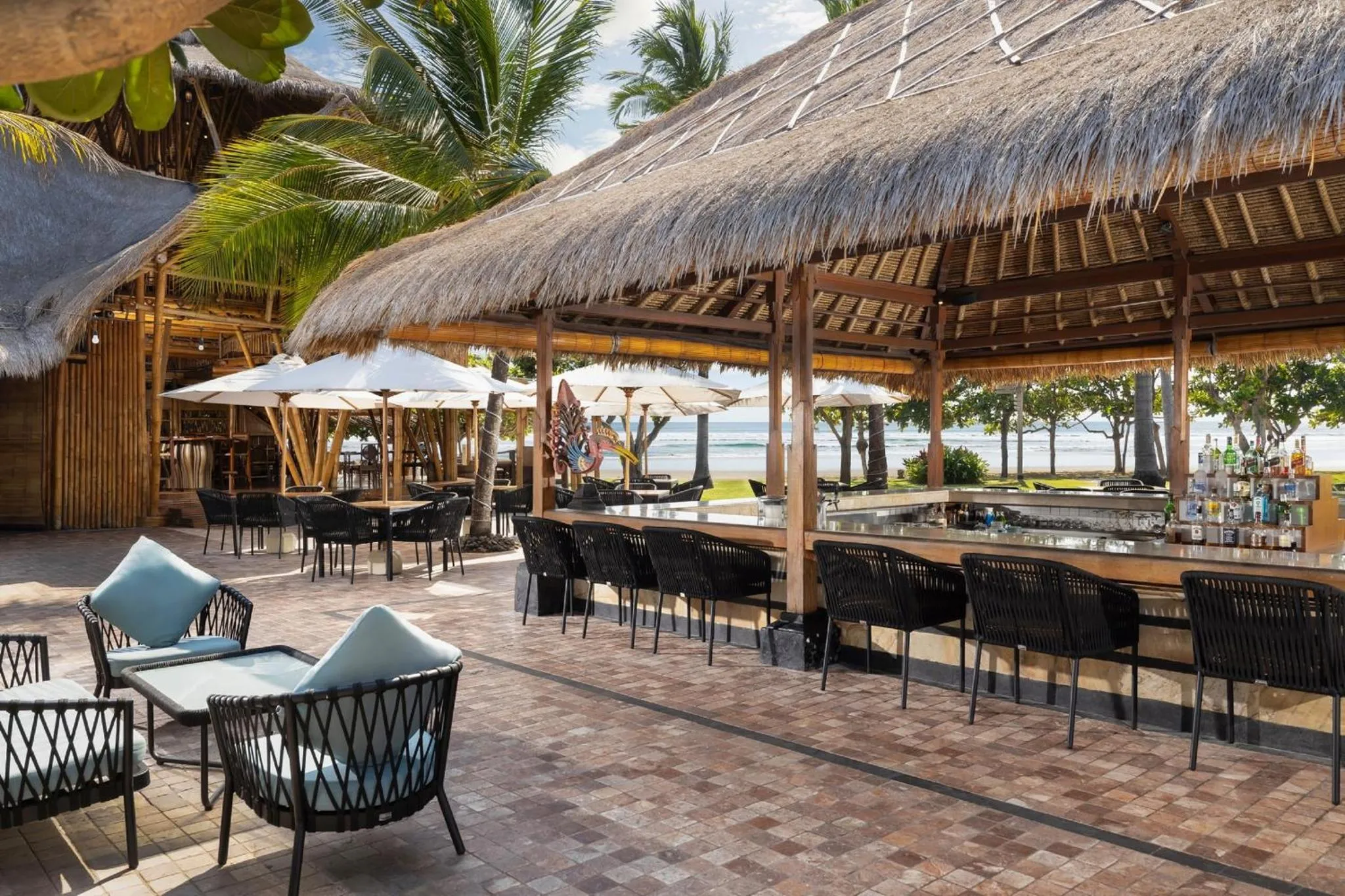 Terrasse ombragée avec bar et mobilier de jardin face à la mer.