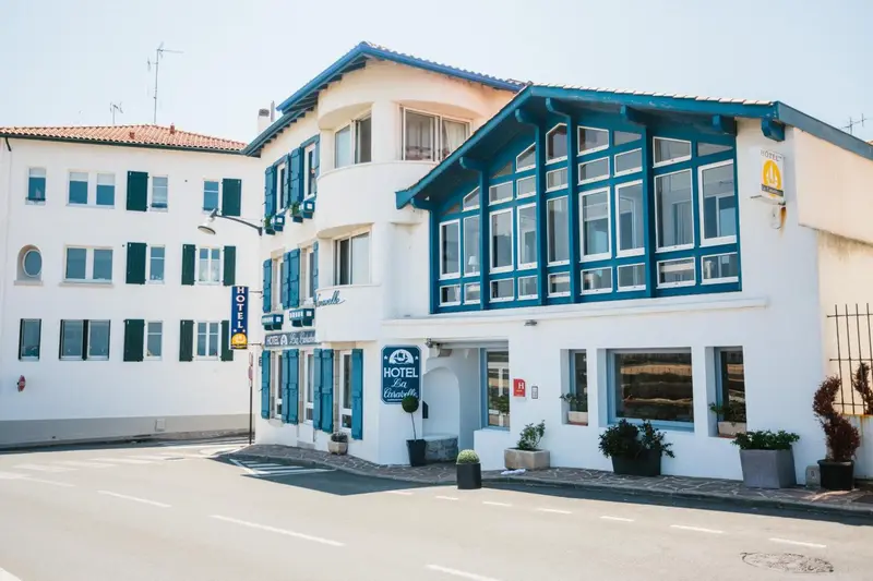 Façade d'un bâtiment blanc et bleu avec des fenêtres et une entrée.