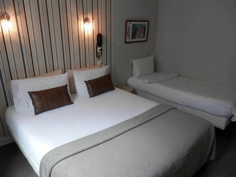 Une chambre avec deux lits simples et un mur rayé.