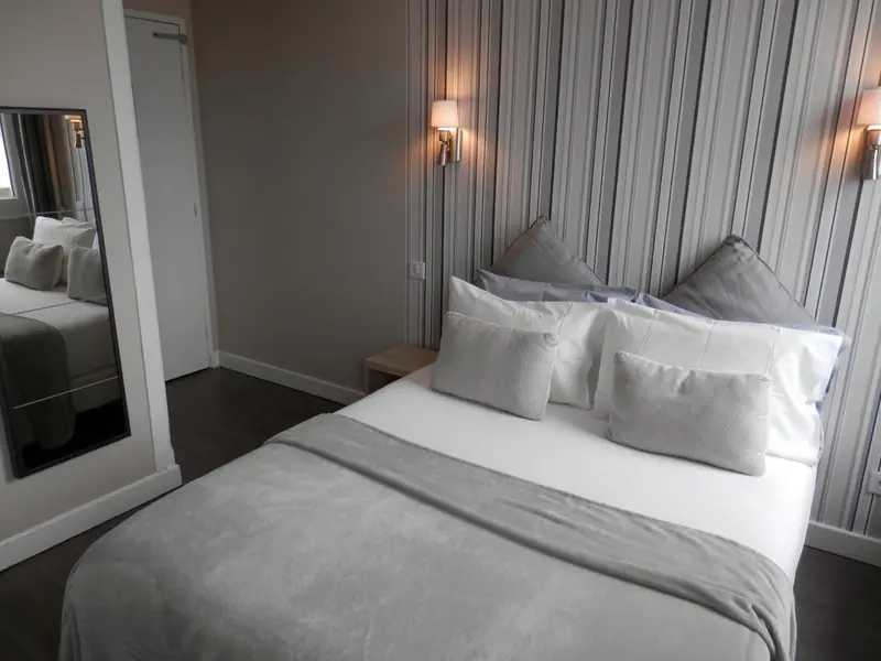 Une chambre avec un grand lit recouvert d'une couette et de plusieurs oreillers.