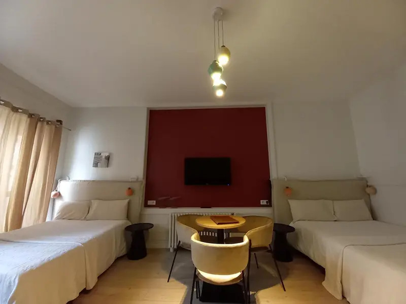 Une chambre lumineuse avec deux lits et un coin repas.