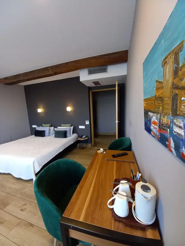 Une chambre lumineuse avec un lit double et un bureau en bois.