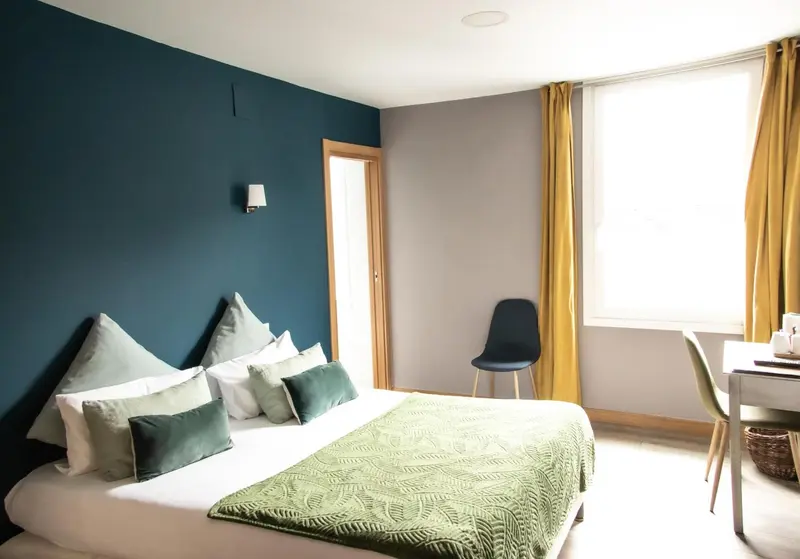 Une chambre lumineuse avec un lit fait et une chaise.
