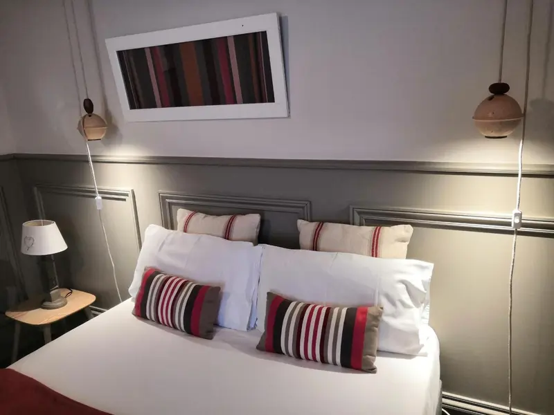 Un lit est fait avec des oreillers et des couvertures blanches et colorées.