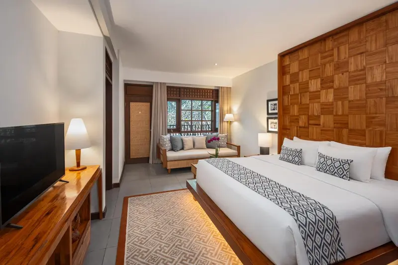 Une chambre lumineuse avec un grand lit et un coin salon.