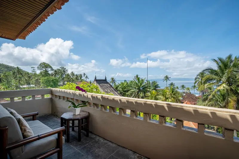 Terrasse avec mobilier d'extérieur donnant sur une végétation luxuriante et la mer.