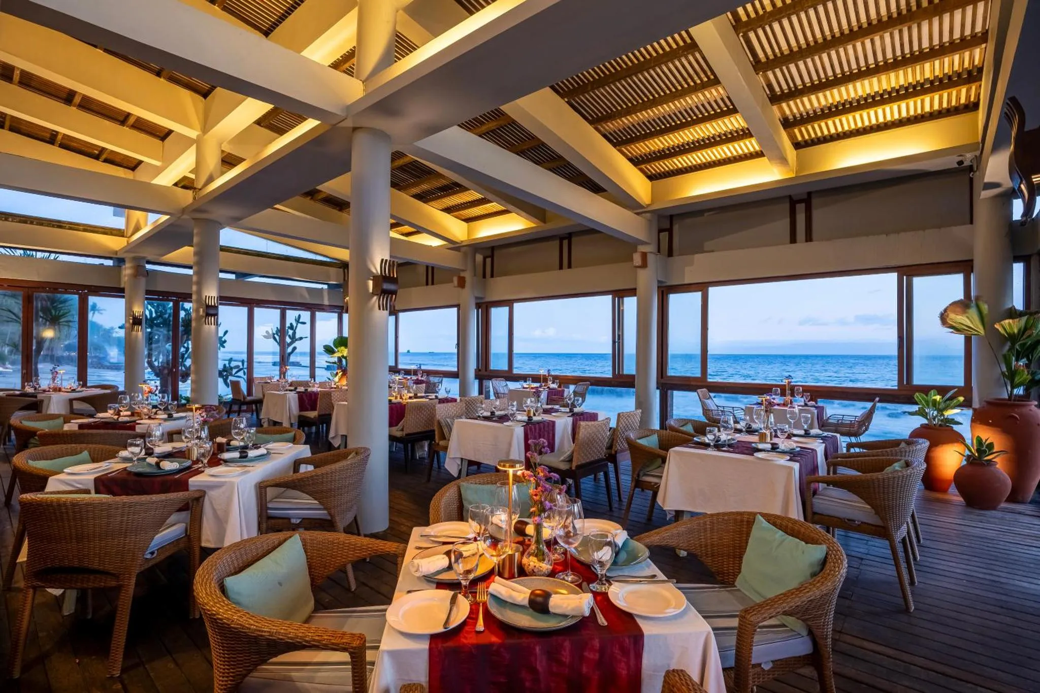 Une salle à manger lumineuse avec des tables dressées face à l'océan.