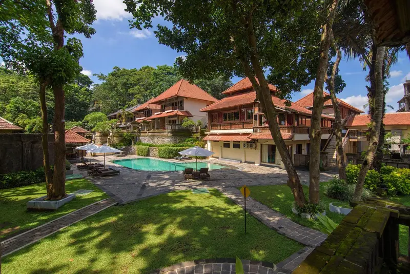 Bâtiment à plusieurs niveaux avec piscine et végétation luxuriante.