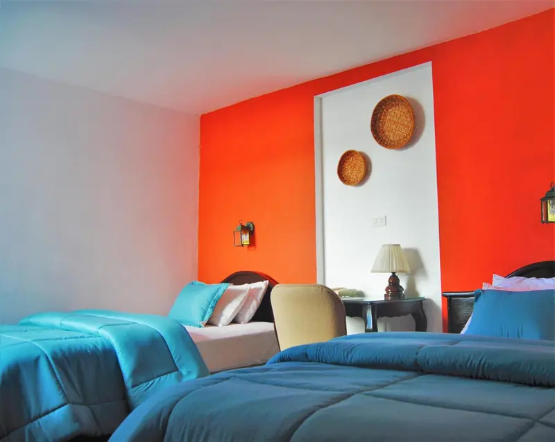 Une chambre lumineuse avec deux lits simples et un fauteuil.