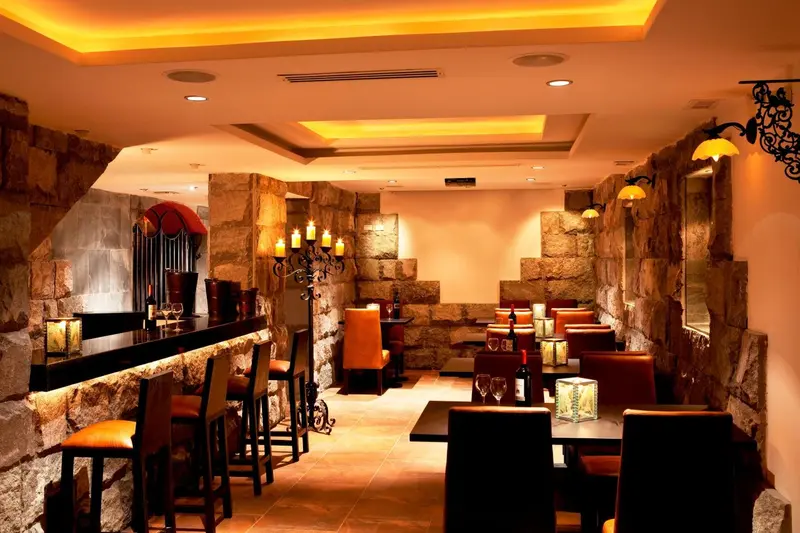 Une salle de restaurant aux murs de pierre et à l'éclairage chaleureux.