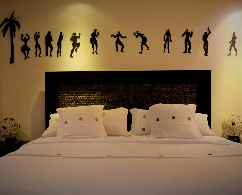 Lit double avec oreillers blancs dans une chambre décorée d'une frise représentant des silhouettes.